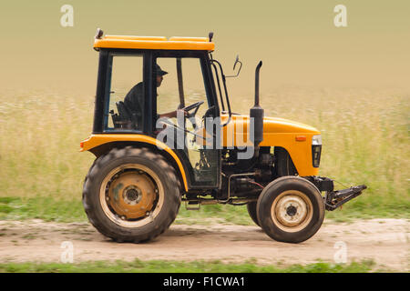 Farm tractor goes on road Stock Photo