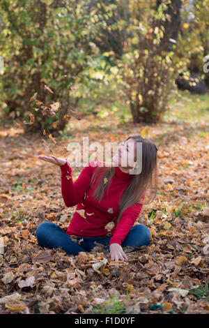 Happy girl playing with yellow autumn leaves in park Stock Photo - Alamy