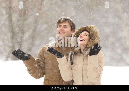 Funny couple watching snow in winter during a snowfall on holidays Stock Photo
