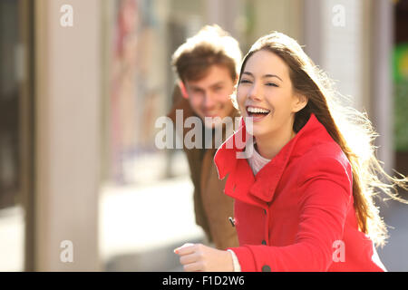Happy couple running in the street in a sunny day Stock Photo
