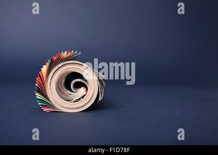 Rolled up magazine isolated on blue background Stock Photo