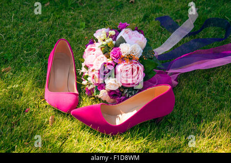 A wedding bouquet with the bride's pink shoes on the grass Stock Photo