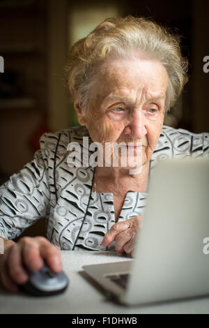 An elderly woman working on a laptop. Senior woman with computer. Stock Photo