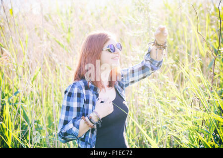 Vintage stylized photo of happy beautiful young woman on summer meadow in tall grass. Stock Photo