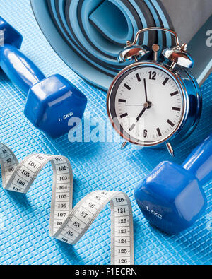 Yoga mat, two dumbbells, tape measure and alarm clock. Stock Photo