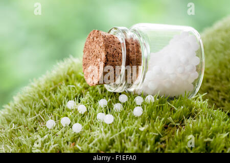 Bottle of homeopathy globules on green moss Stock Photo