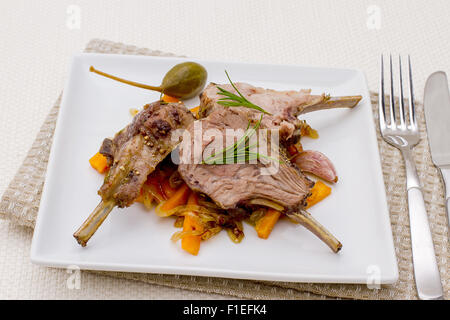 Grilled racks of lamb with carrot, onion, garlic and capers Stock Photo