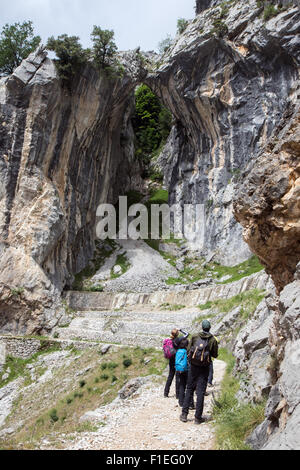 Walkers stop to view a natural hole in the limestone on the trail through the Cares Gorge near Poncebos in the Picos de Europa Stock Photo