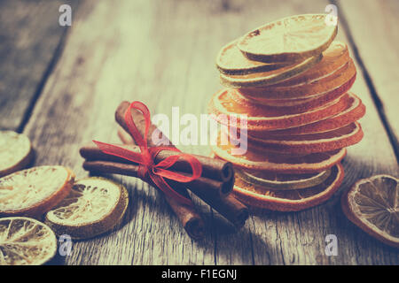 Dried orange and lemon slices, lime and cinnamon sticks on table. Retro styled photo. Stock Photo