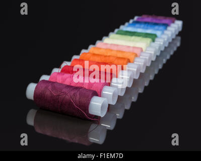 coils with multi-colored sewing threads on a black background Stock Photo
