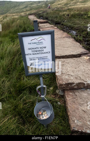 A collecting bucket on the path up Whernside in the Yorkshire Dales, asking for donations towards the route’s restoration Stock Photo