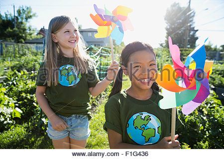 Portrait smiling girls with pinwheels in sunny garden