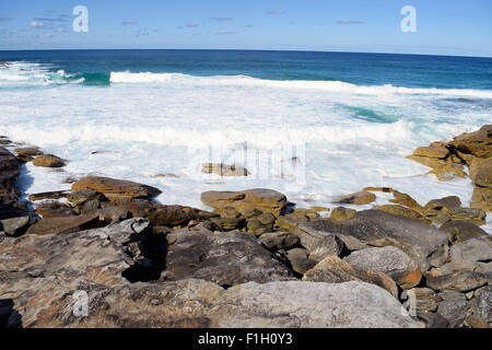 Foam and water crashing on the rocks covered in moss. Stock Photo