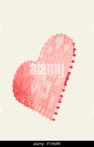 Red plastic heart hanging in mid air. Conceptual image of love, and romantic feelings. Stock Photo