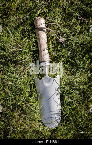 Close up of small garden spade with wooden handle lying on grass Stock Photo
