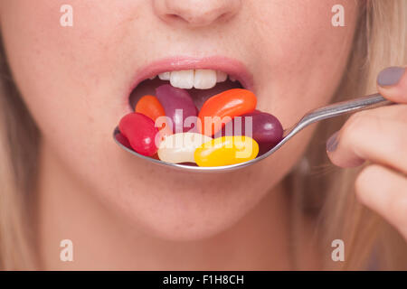 Close up of woman taking pills on a spoon into her mouth. Stock Photo