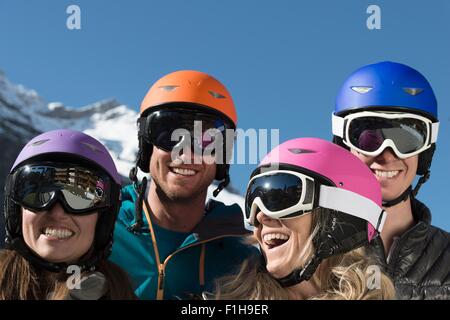 Four friends wearing ski helmets and goggles, laughing Stock Photo