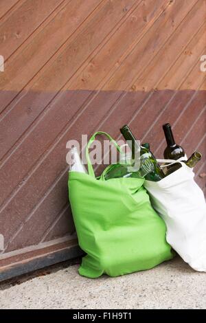Two reusable shopping bags full of bottles for recycling in yard Stock Photo