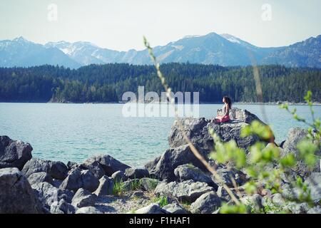 Mid adult woman, sitting on rock, in yoga position Stock Photo