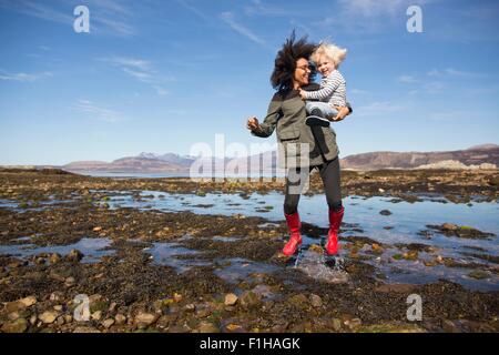 Mother holding son jumping in Loch Eishort, Isle of Skye, Hebrides, Scotland Stock Photo
