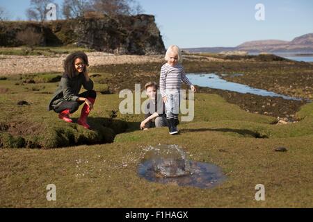 Boy throwing rock into puddle, Isle of Skye, Hebrides, Scotland Stock Photo
