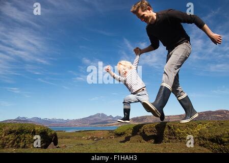 Father and son holding hands running, Isle of Skye, Hebrides, Scotland Stock Photo