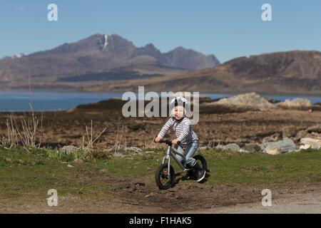 Boy riding bike, Lake Eishort, Isle of Skye, Hebrides, Scotland Stock Photo