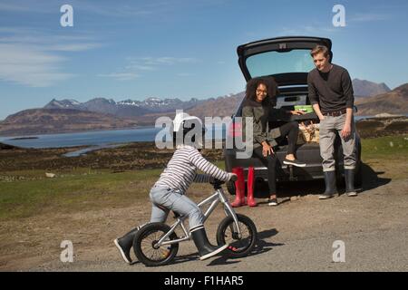 Parents watching son ride bike, Loch Eishort, Isle of Skye, Hebrides, Scotland Stock Photo