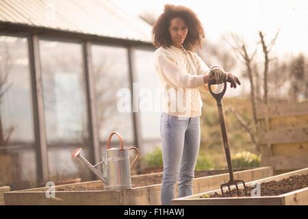 Mid adult woman by raised bed with garden fork, portrait Stock Photo