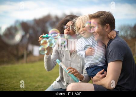 Mother blowing bubbles, father holding son Stock Photo