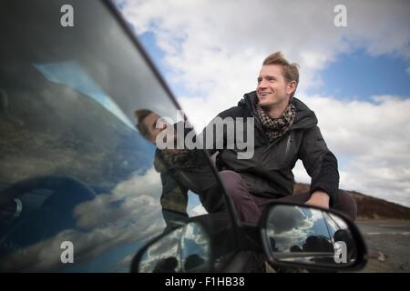 Mid adult man by car looking away, smiling Stock Photo