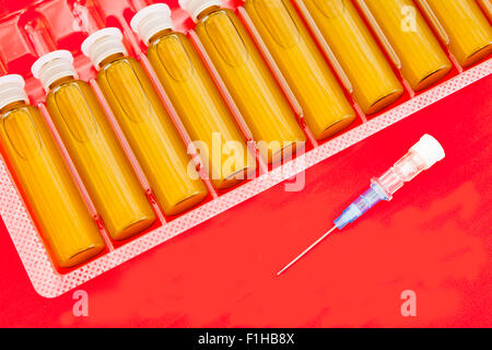 Medical blisters and blue needle isolated in red Stock Photo