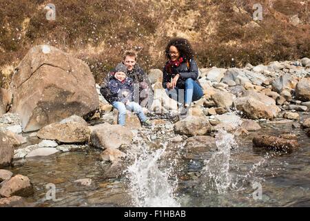 Family throwing stones in pond, Fairy Pools, Isle of Skye, Hebrides, Scotland Stock Photo