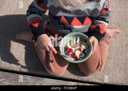 Boy holding bowl of fruit, high angle Stock Photo