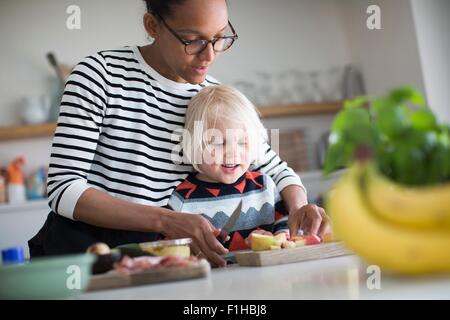 Mother helping sone prepare food in kitchen Stock Photo