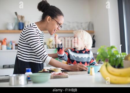 Son feeding mother food in kitchen Stock Photo