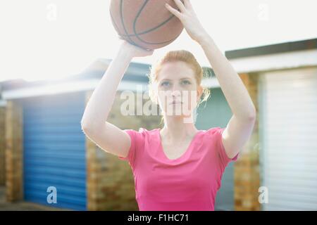 Portrait of woman holding basketball above head Stock Photo