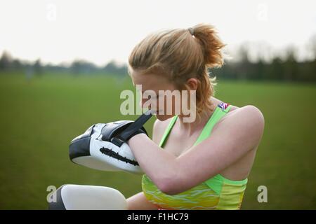 Portrait of a woman putting on boxing pads in the park