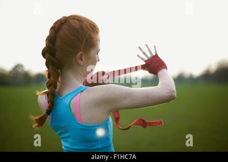 Portrait of a woman putting on boxing gloves straps in the park Stock Photo