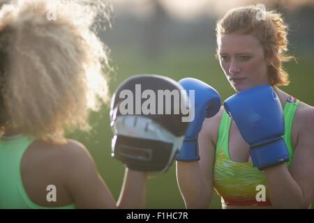 Two women exercising with boxing gloves in the park