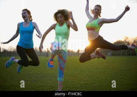 Portrait of three women jumping in the park Stock Photo