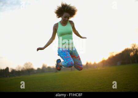 Portrait of woman jumping in park Stock Photo