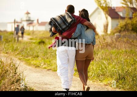 Rear view of young couple strolling with arms around each other
