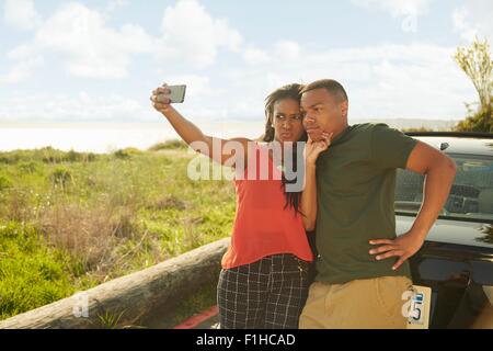 Young couple using smartphone, taking selfie, making faces Stock Photo