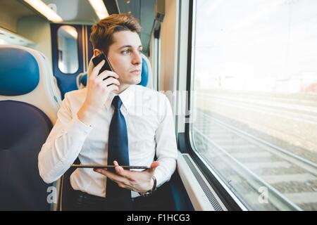 Portrait of young businessman commuter using digital tablet on train. Stock Photo