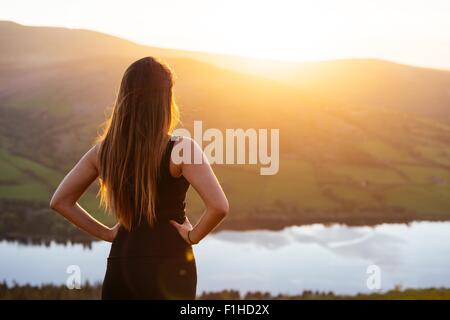 Rear view of young woman looking out over Talybont Reservoir in Glyn Collwn valley, Brecon Beacons, Powys, Wales Stock Photo