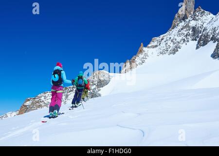 Rear view of mature male and female skiers moving up Mont Blanc massif, Graian Alps, France Stock Photo