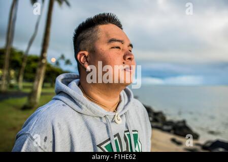 Young man looking out at sunrise from Kaaawa beach, Oahu, Hawaii, USA