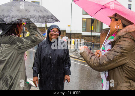 London, August 31st 2015. Labour mayoral candidate Diane Abbot chates with two women waiting for the procession to begin as revellers ignore the inclement weather to enjoy day two of the Notting Hill Carnival. Credit:  Paul Davey/Alamy Live News Stock Photo