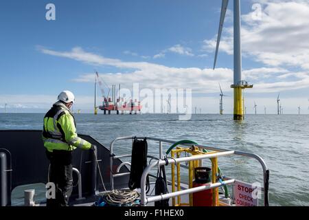 Worker looking out from ship to offshore wind farm and construction ship